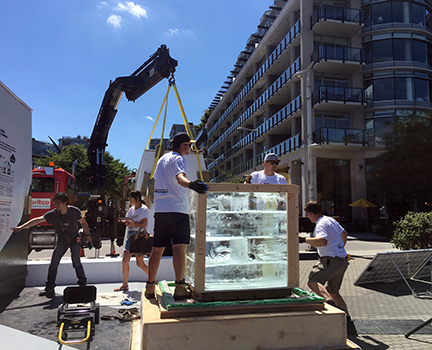 Loading ice onto the BC Building Code box platform under bright sun.